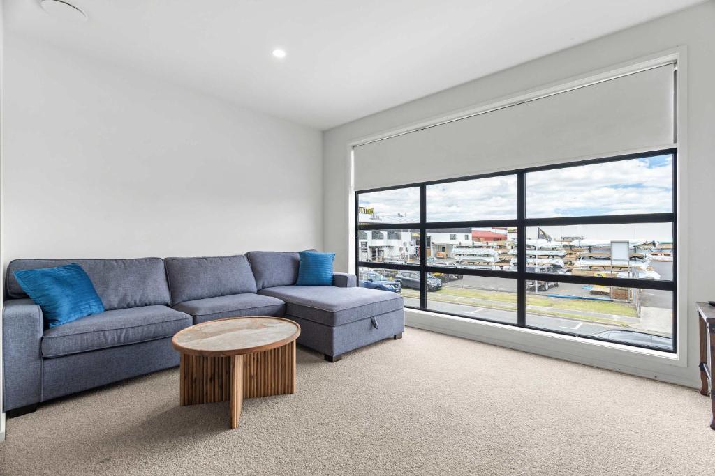 a living room with a couch and a large window at Coastal Bliss in Mount Maunganui