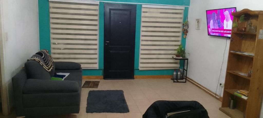 Sala de estar con puerta, sofá y TV en Aloha, en Río Gallegos