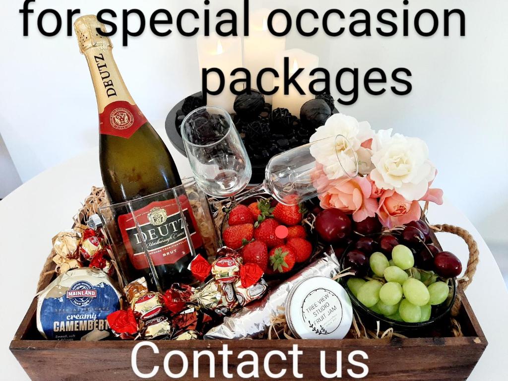 a bottle of wine and a basket of fruit at Tree View Studio in Tauranga