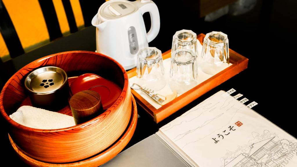 a wooden tray with glasses and a tea kettle on a table at 熱海山荘 in Atami