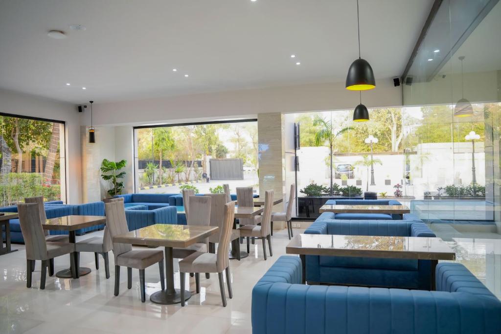 a restaurant with blue couches and tables and chairs at Lahore Grande Boutique Hotel in Lahore