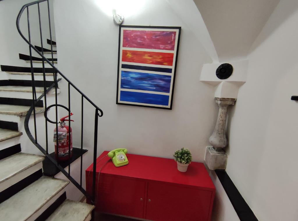 a living room with a red cabinet and stairs at Le Grazie Maisons Genova in Genoa