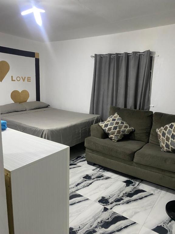 a living room with a couch and a bed at White Room Sparks Guesthouse in Spanish Town