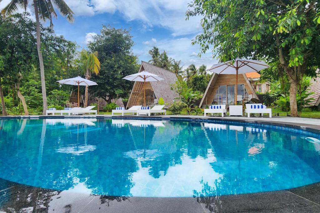 a swimming pool in a resort with chairs and umbrellas at Nature Hill Penida in Nusa Penida