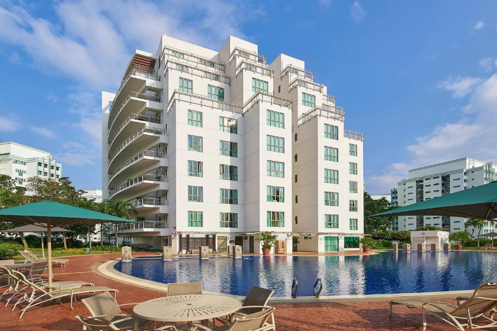 un edificio con piscina, mesas y sillas en Village Residence Hougang by Far East Hospitality en Singapur