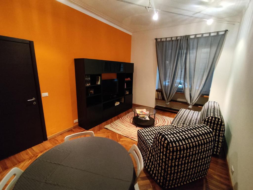 un salon avec une table, des chaises et une télévision dans l'établissement Bell'appartamento in Cit Turin, Interamente ristrutturato, à Turin