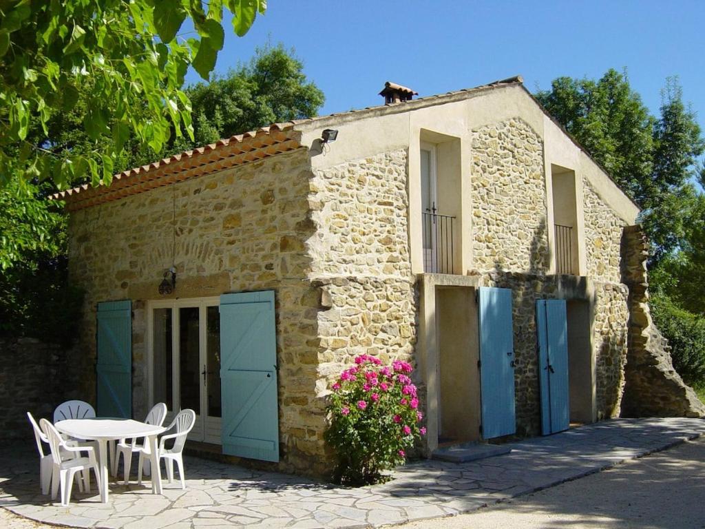 - un petit bâtiment en pierre avec des portes bleues, une table et des chaises dans l'établissement La Bergerie, à Deaux