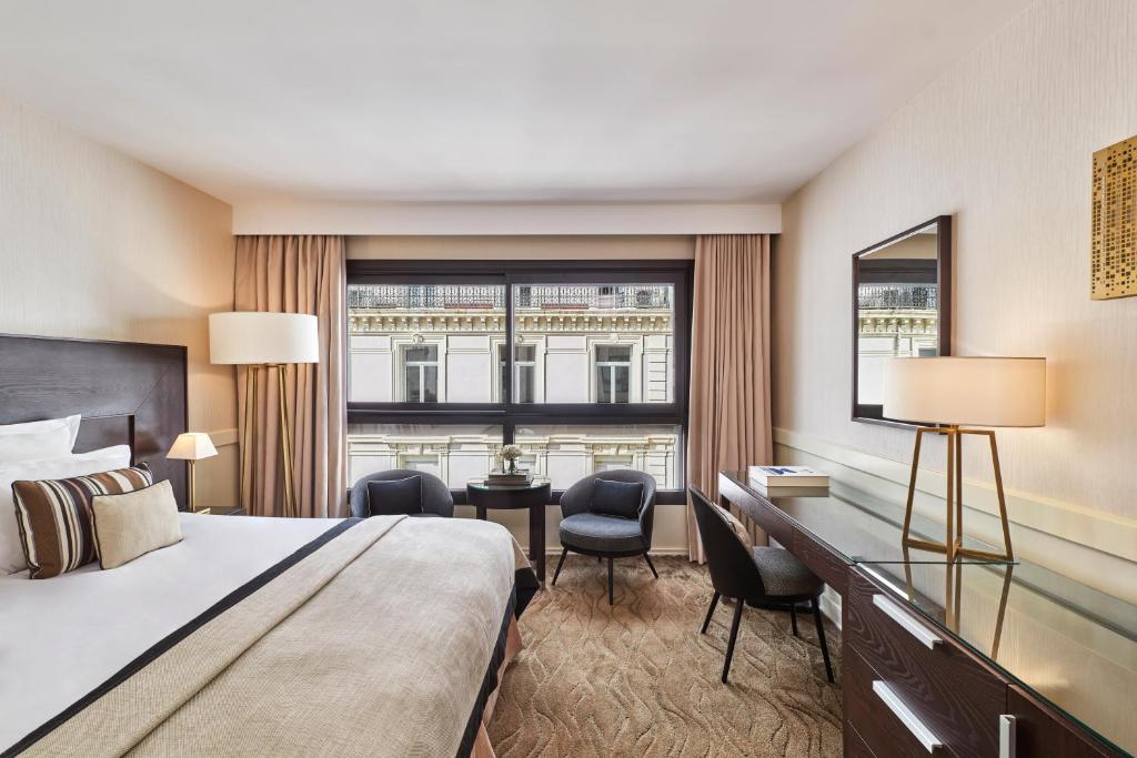 a hotel room with a bed and a desk and a window at Hôtel Barrière Le Gray d'Albion in Cannes