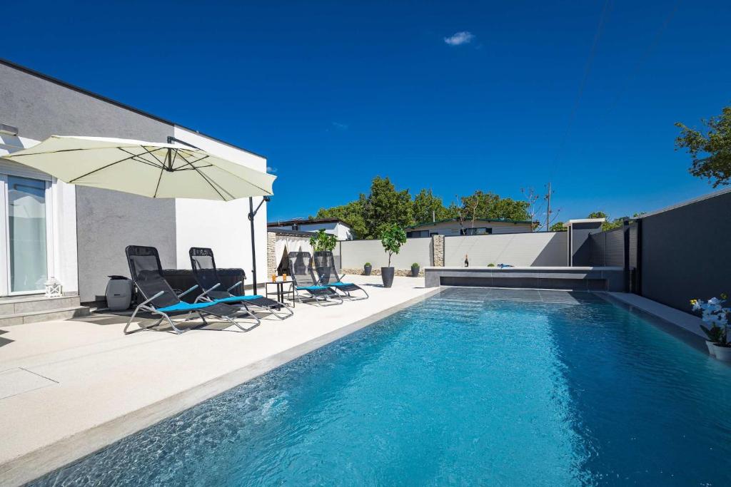 a swimming pool with two chairs and an umbrella at Villa Marsel in Mednjan