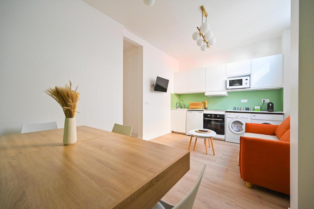 Il dispose d'une cuisine et d'un salon avec une table en bois et un canapé orange. dans l'établissement Grand 2P - Neuf - Proche Paris, aux Lilas