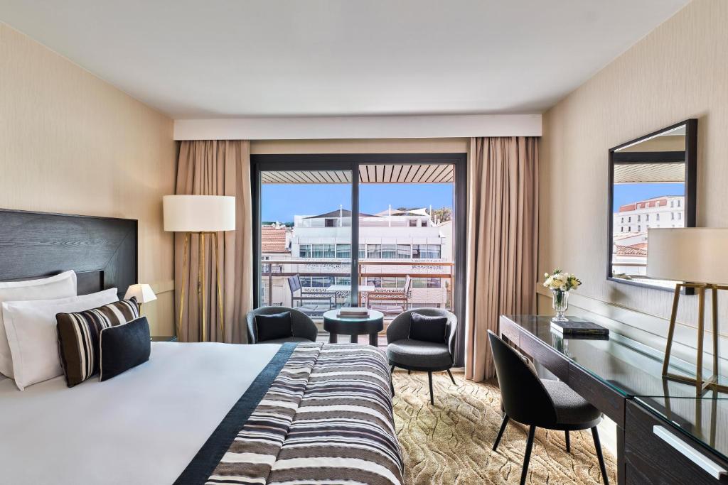 a hotel room with a bed and a desk and a window at Hôtel Barrière Le Gray d'Albion in Cannes