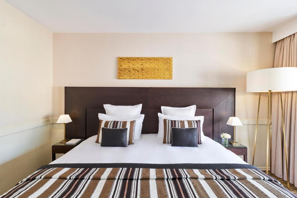 a bedroom with a large white bed with two pillows at Hôtel Barrière Le Gray d'Albion in Cannes
