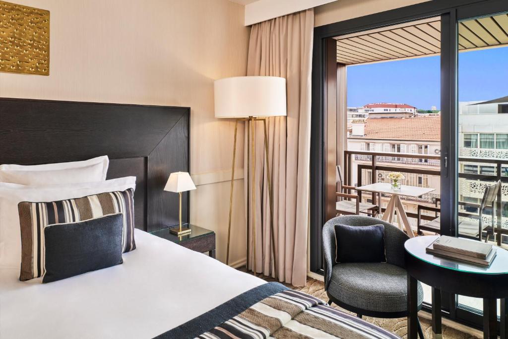 a hotel room with a bed and a balcony at Hôtel Barrière Le Gray d'Albion in Cannes