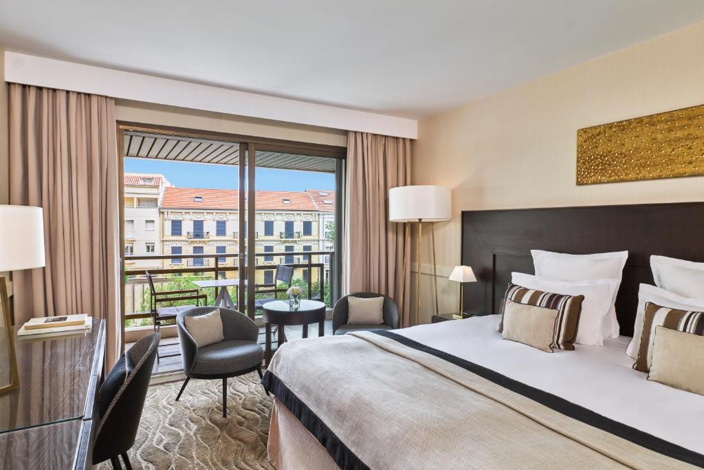 a hotel room with a bed and a balcony at Hôtel Barrière Le Gray d'Albion in Cannes