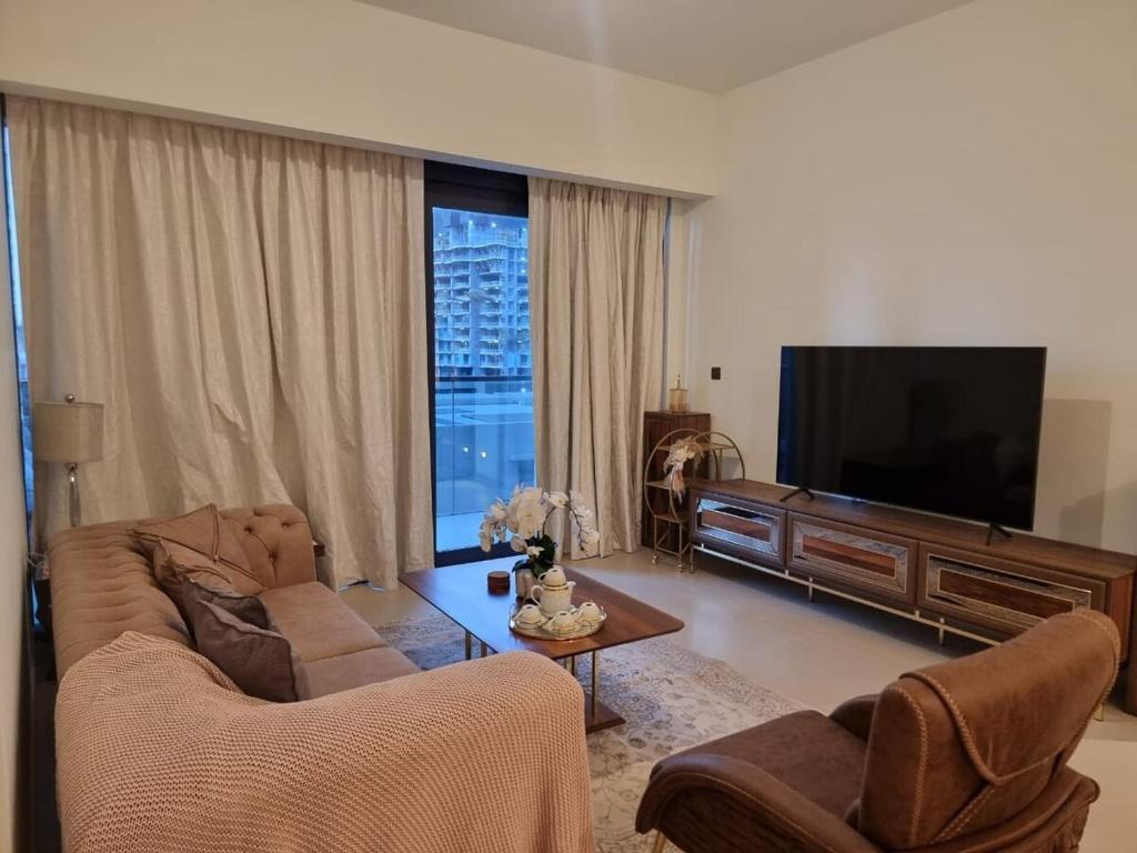 a living room with a couch and a flat screen tv at Luxury 2 Bedroom Act 1 Apartment in Dubai