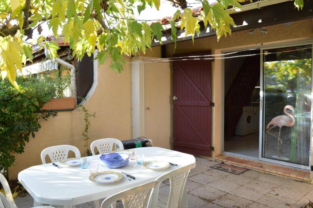 - une table blanche avec des chaises et un oiseau dans la cour dans l'établissement Maison 3 pièces mezzanine 8 couchages sc105-013, à Saint Cyprien Plage
