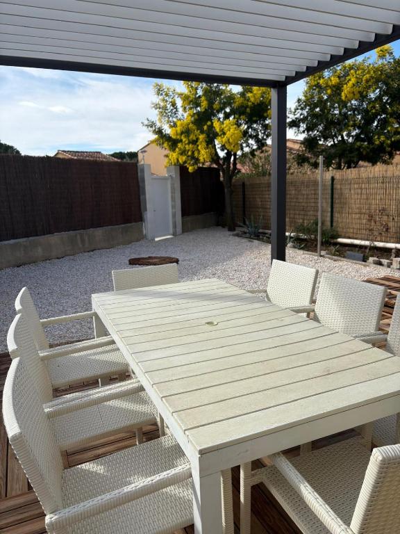 - une table de pique-nique et des chaises blanches sous une pergola dans l'établissement St Cyprien Belle maison renovee avec jardin 4 a 6 p, à Saint-Cyprien