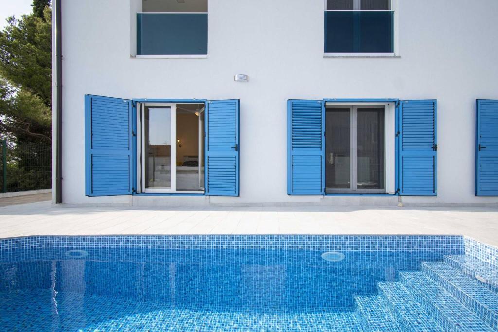 Casa con ventanas con persianas azules y piscina en Villa Blue Chill, en Brodarica