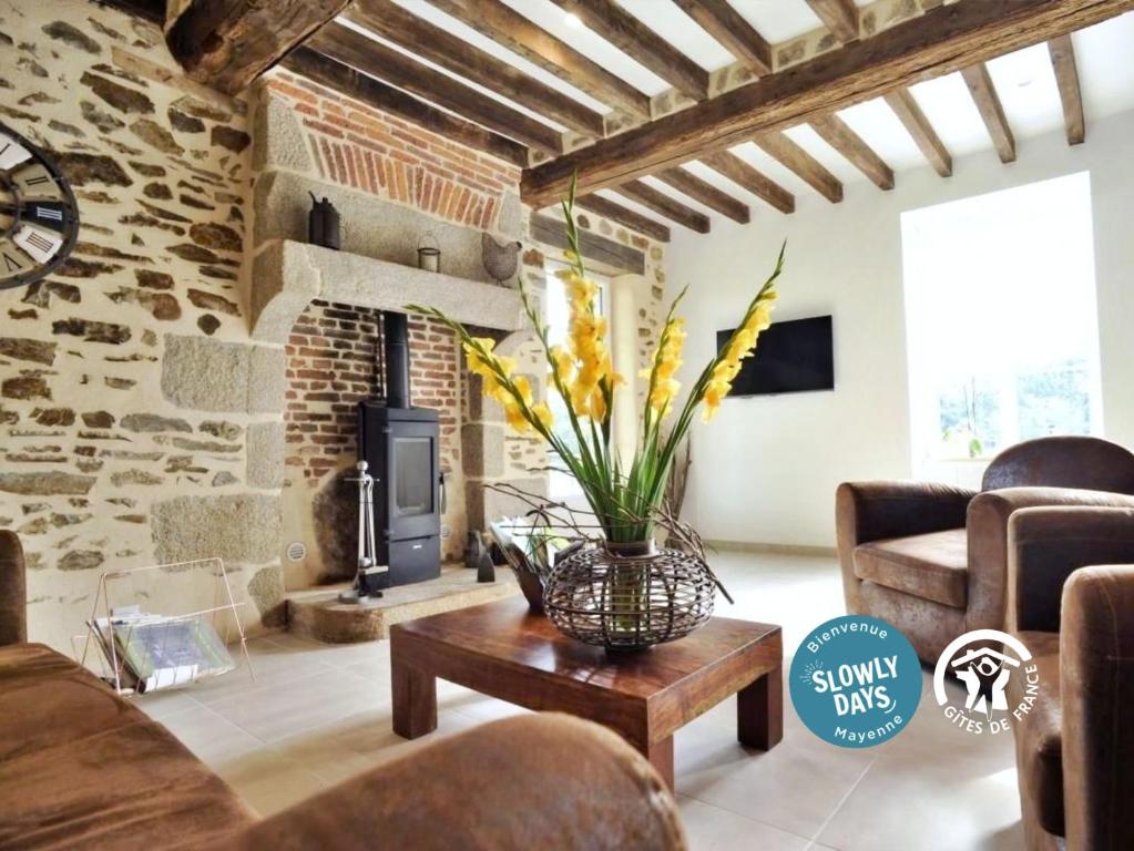 a living room with a fireplace and a vase of flowers on a table at La petite vallée in Saint-Calais-du-Désert