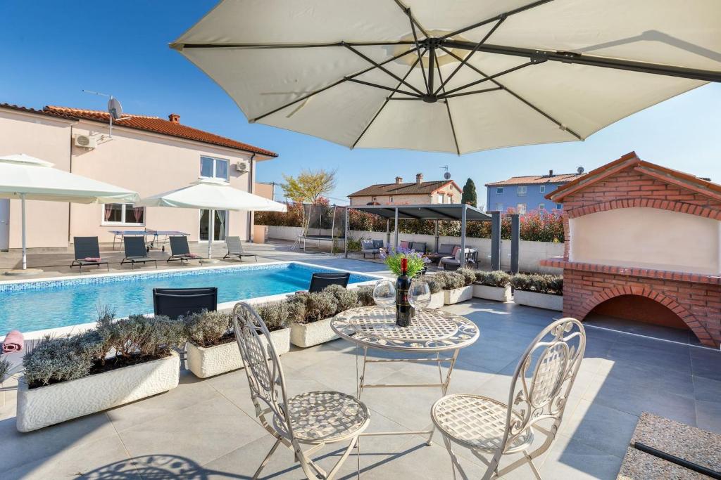 eine Terrasse mit Tisch, Stühlen und Sonnenschirm in der Unterkunft Villa Berg II in Valbandon