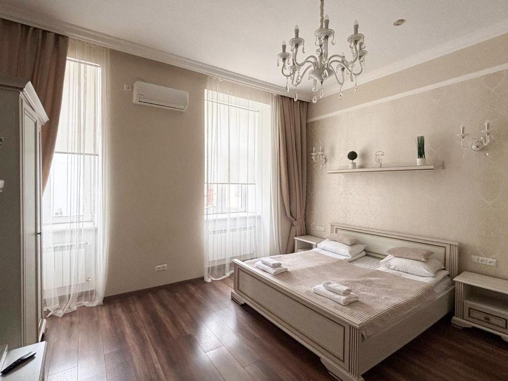 - une chambre avec un lit, 2 fenêtres et un lustre dans l'établissement Historical Center of Lviv, à Lviv