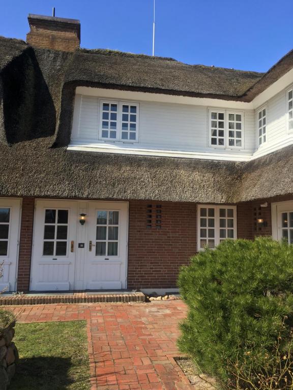 a brick house with white doors and a tile roof at Sylt-Traum Kampen in Kampen