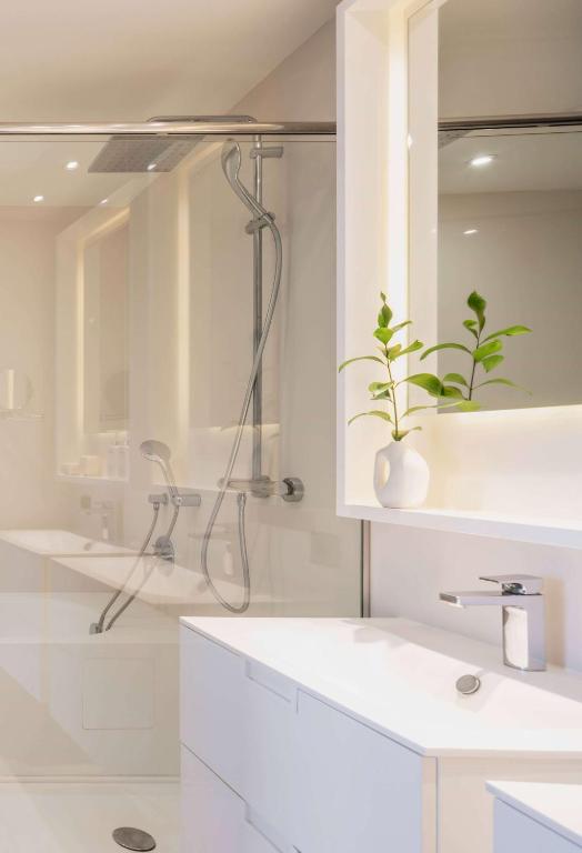 a white bathroom with a shower and a sink at Hotel Don Pepe Gran Meliá in Marbella