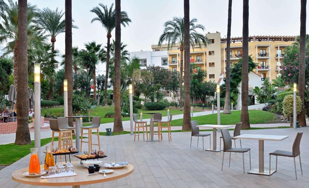 patio ze stołami, krzesłami i palmami w obiekcie Sol Torremolinos - Don Pedro w mieście Torremolinos