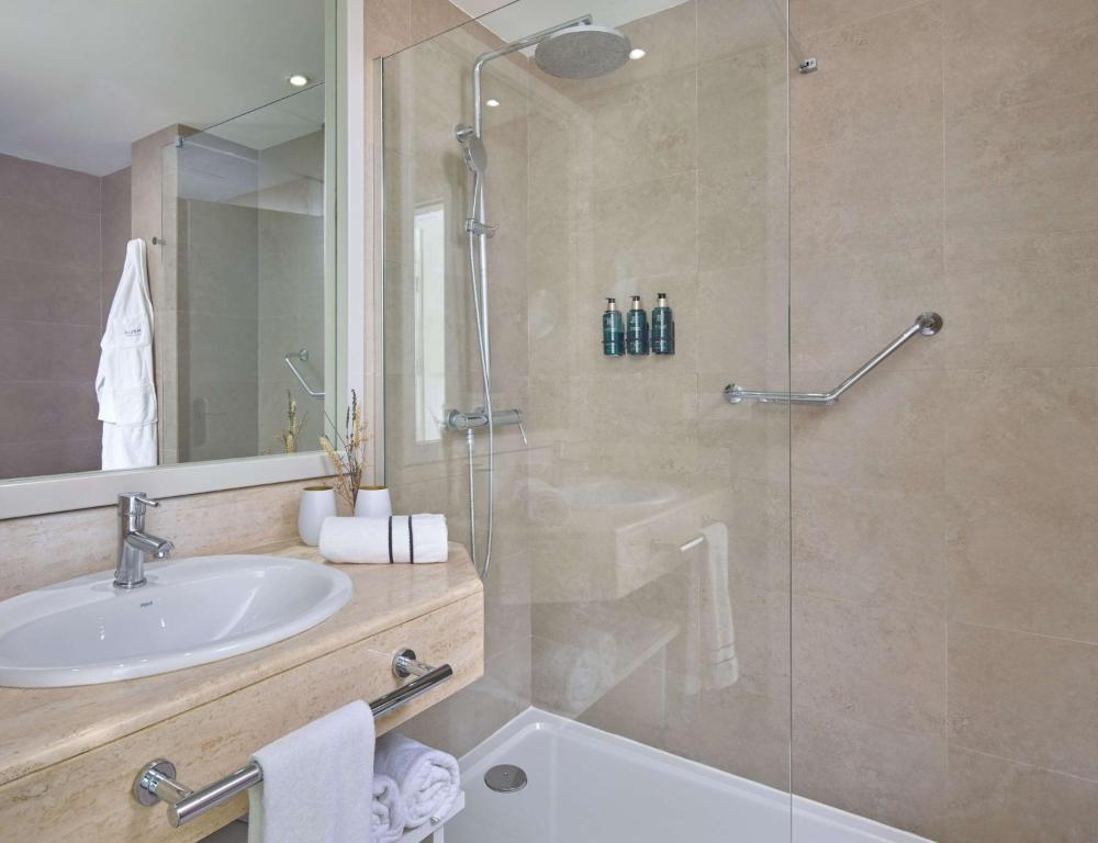 a bathroom with a sink and a glass shower at Meliá Cala Galdana in Cala Galdana