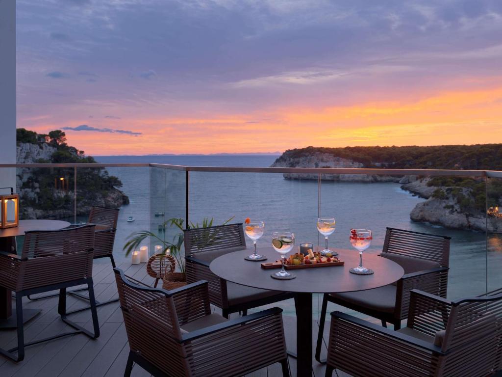 a patio with a table with glasses of wine at Meliá Cala Galdana in Cala Galdana