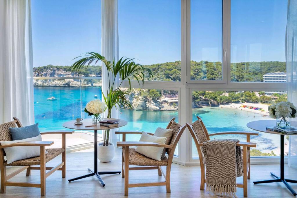 a room with tables and chairs and a view of the ocean at Meliá Cala Galdana in Cala Galdana