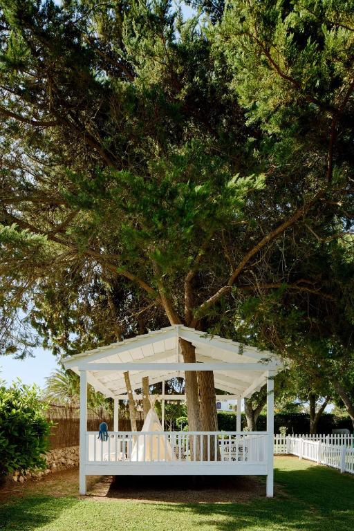 a white gazebo sitting under a tree at Meliá Cala Galdana in Cala Galdana