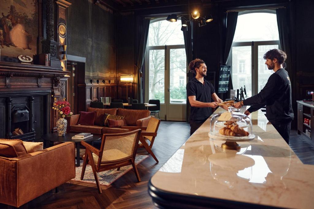 zwei Personen, die um einen Tisch in einem Zimmer stehen in der Unterkunft The Elephant Hostel in Amsterdam