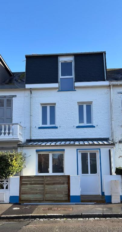 une maison blanche avec une clôture en bois devant elle dans l'établissement Maison avec terrasse, 10 couchages, à 200 m de la plage, à Berck-sur-Mer