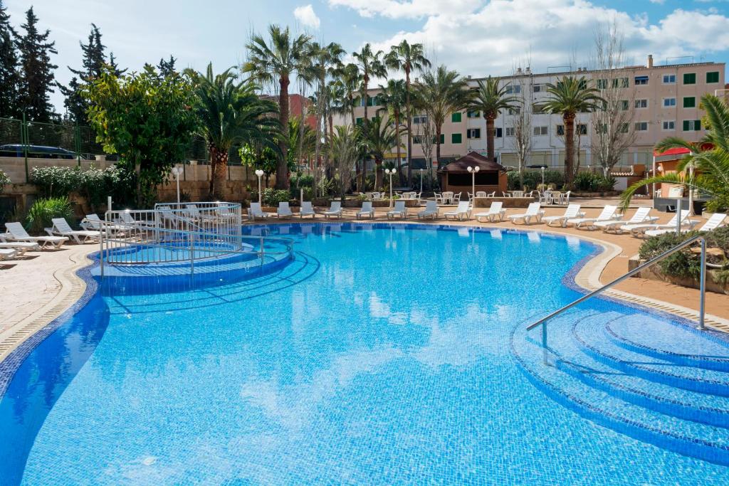 einen großen Pool mit Stühlen und Palmen in der Unterkunft HSM Don Juan in Magaluf