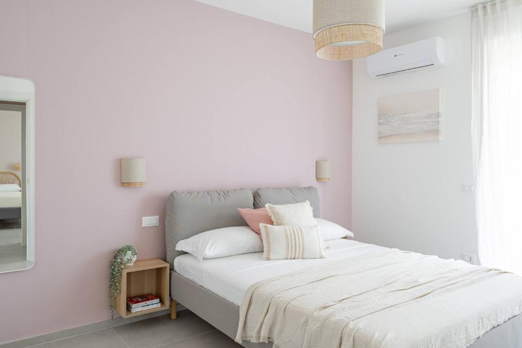 - une chambre blanche avec un lit doté de draps blancs et d'oreillers roses dans l'établissement Villa Novelli - YourPlace Abruzzo, à Fossacesia