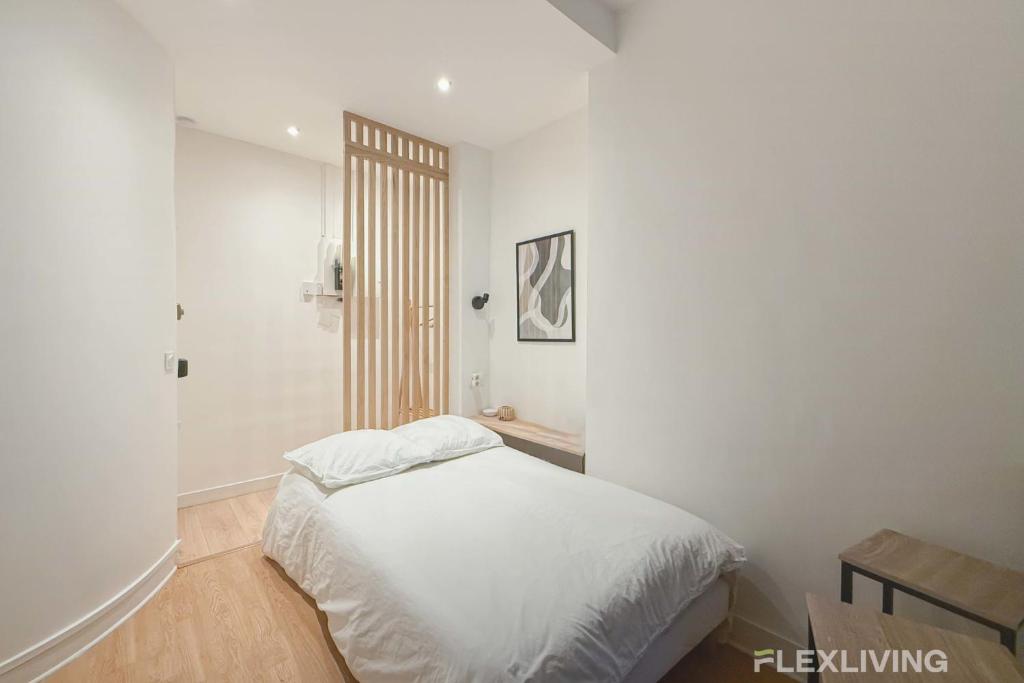- une chambre blanche avec un lit et une salle de bains dans l'établissement Flexliving - Studio - La Fayette, à Paris