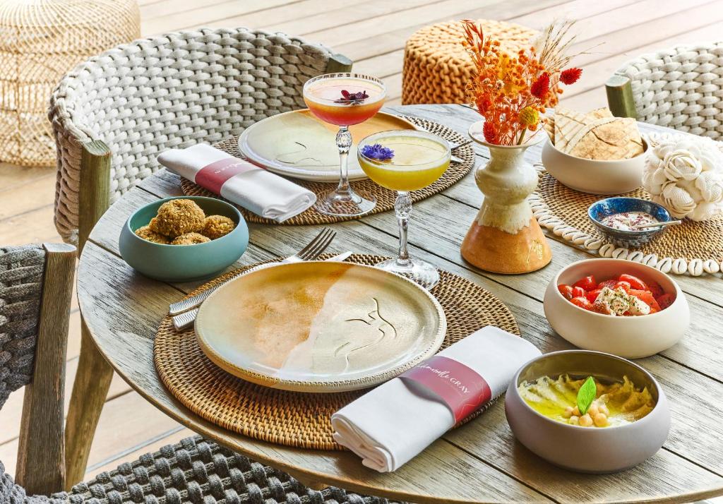 a wooden table topped with plates and bowls of food at Hôtel Barrière Le Gray d'Albion in Cannes