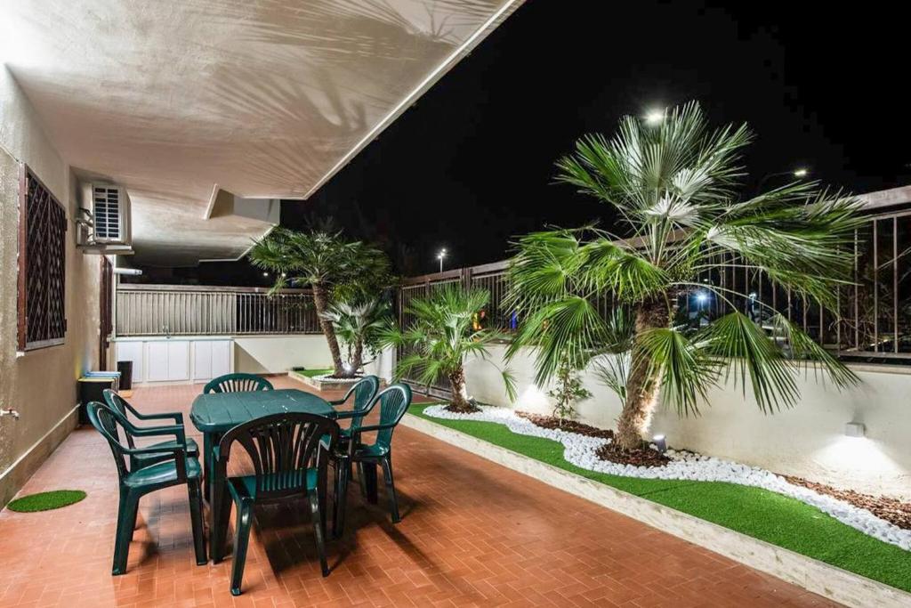 a patio with a table and chairs and palm trees at Fronte Mare Pescara - YourPlace Abruzzo in Pescara
