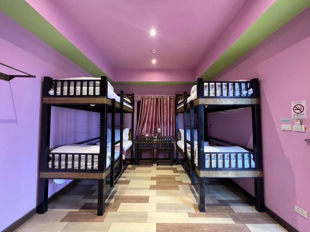 Zimmer mit 3 Etagenbetten und lila Wänden in der Unterkunft Changpuak Boutique House in Chiang Mai