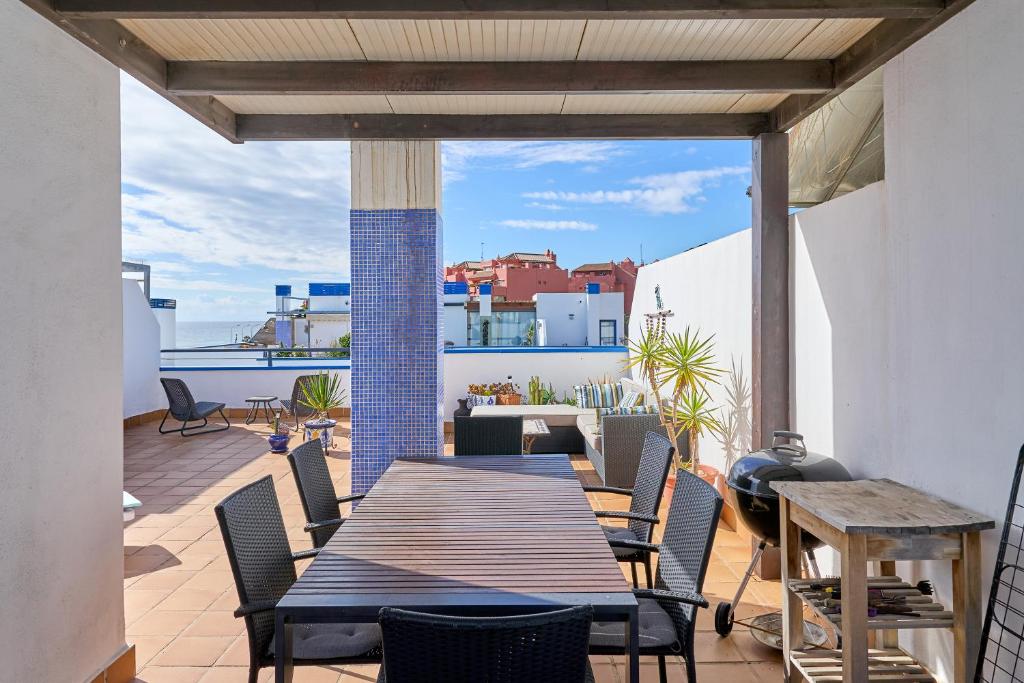 a patio with a wooden table and chairs on a balcony at Penthouse by the beach in Torrox Costa