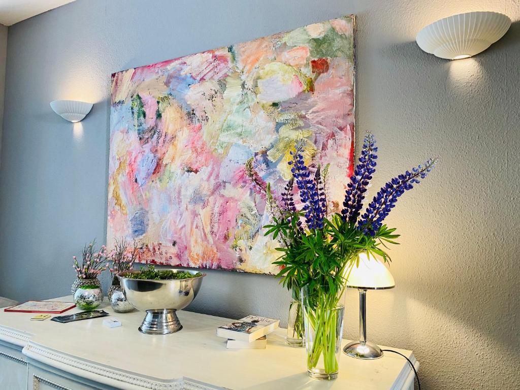 un dipinto su un muro con un vaso di fiori su una scrivania di Bärliner Hotel a Erfurt