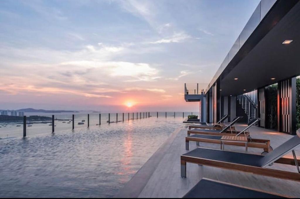a group of benches sitting on the side of a building with the sunset at The Base海景网红顶层无边泳池 双卧室套房 in Pattaya Central