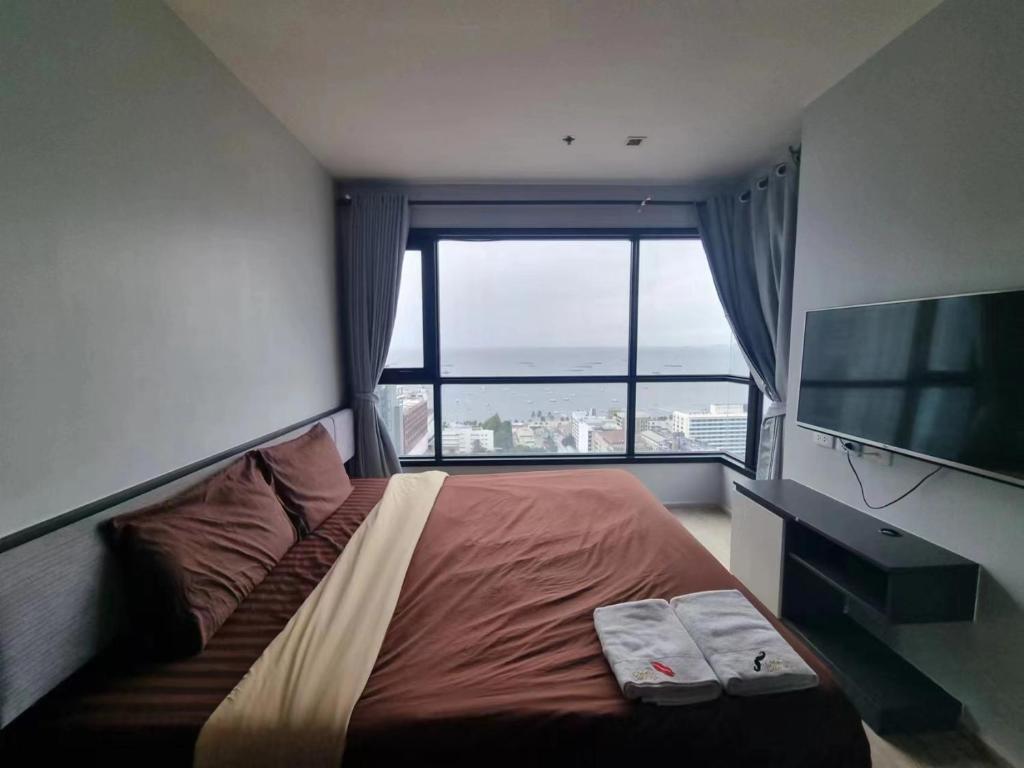 a bedroom with a bed and a flat screen tv at The Base海景网红顶层无边泳池 双卧室套房 in Pattaya Central