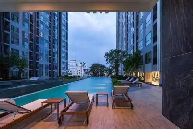 a swimming pool in a building with chairs and tables at The Base海景网红顶层无边泳池 双卧室套房 in Pattaya Central