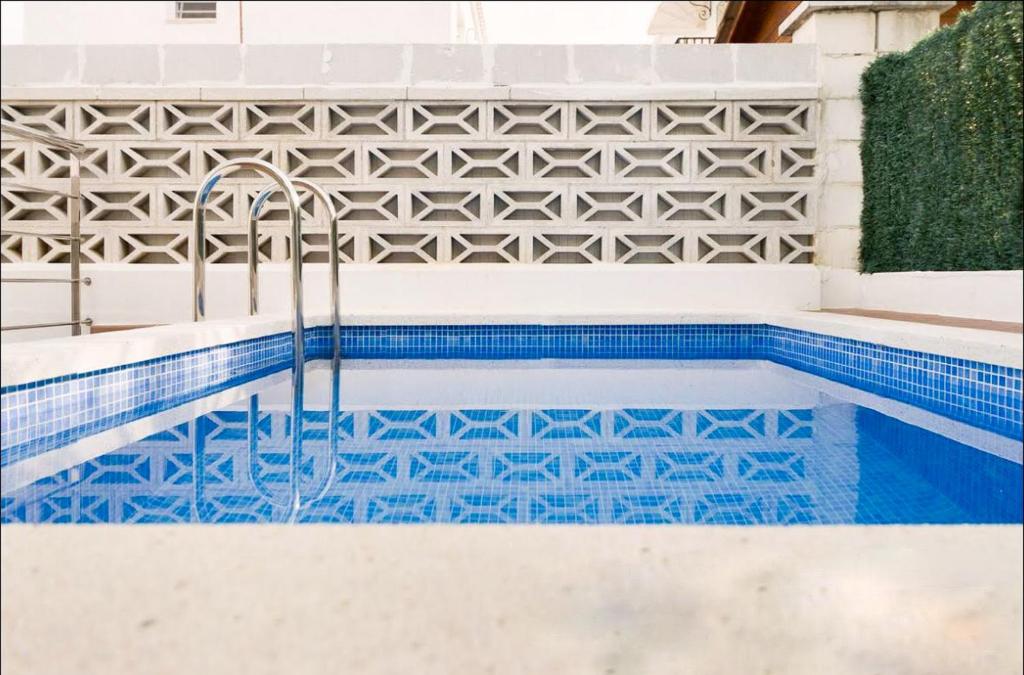 a swimming pool with blue tiles and a fountain at Cozy Apartment Rocamar in Sant Pere de Ribes