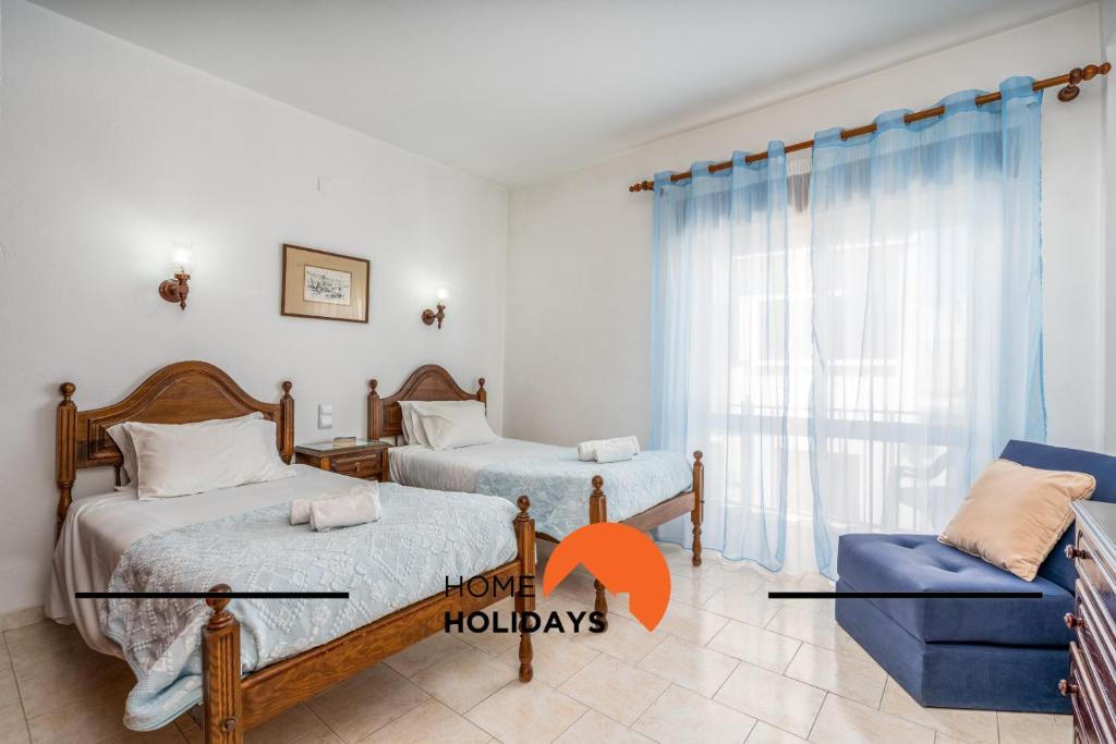 a bedroom with two beds and a blue chair at #258 Travessa do Mar F by Home Holidays in Albufeira