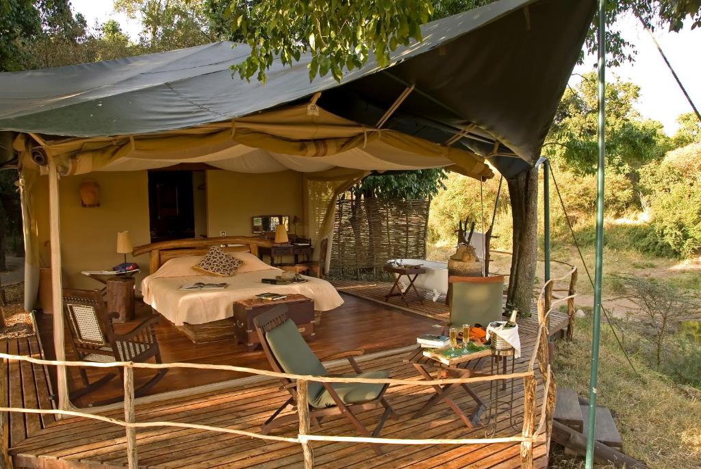 Mara Explorer Tented Camp في Aitong: خيمة على طاولة وكراسي على سطح السفينة