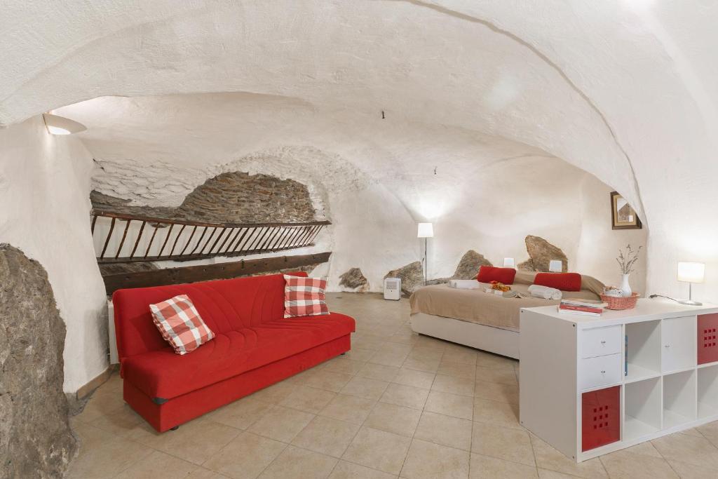 Un dormitorio con una cama y un sofá rojo. en La Casetta Del Borgo - Happy Rentals, en Usseaux