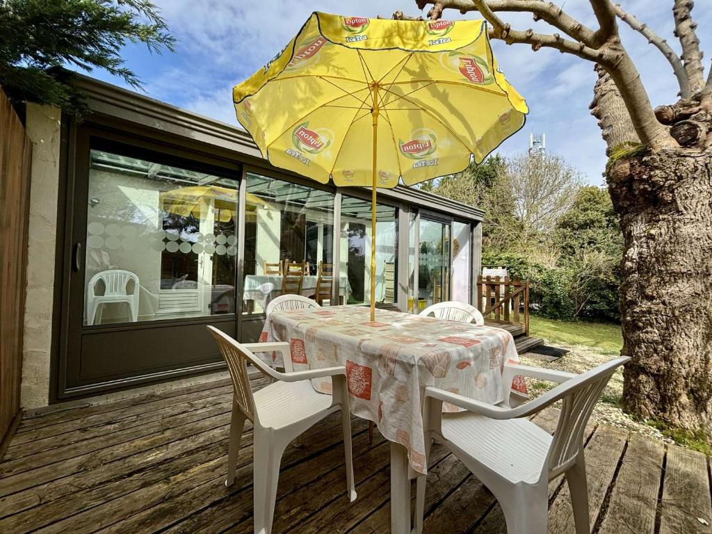 une table et des chaises avec un parasol jaune sur une terrasse dans l'établissement Mais 3 pièces 4 couchages SAINT GEORGES D'OLERON SGO000-102, à Saint-Georges-dʼOléron